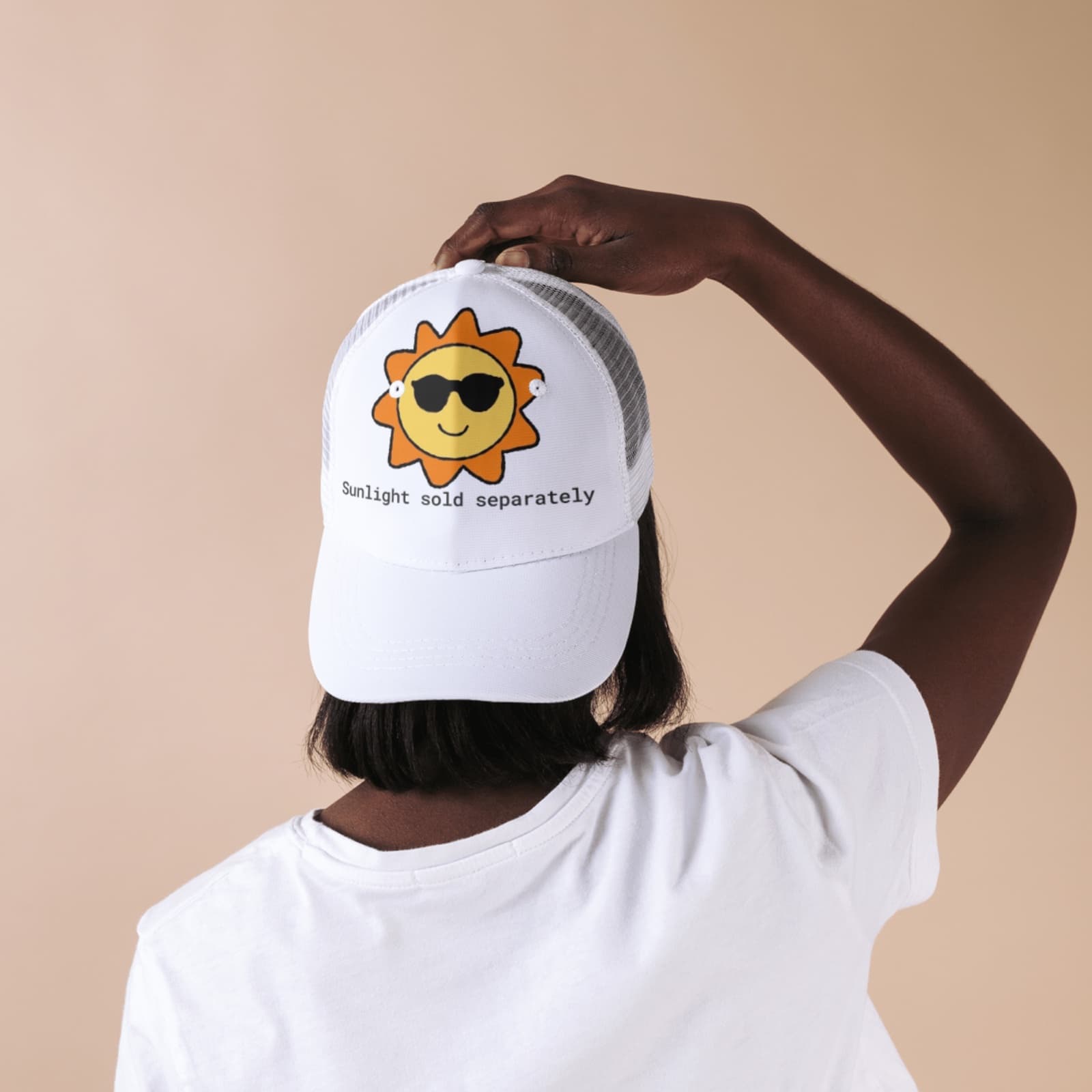 White trucker cap printed with a cartoon sun in sunglasses and the words Sunlight sold separately